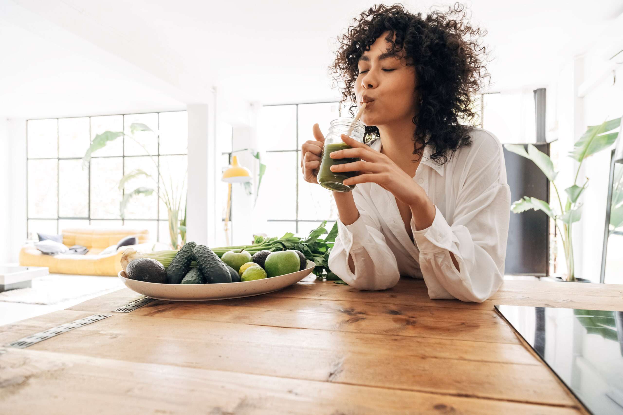 Young african american woman drinking green juice with reusable