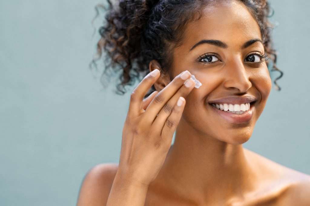 Woman applying moisturiser on face