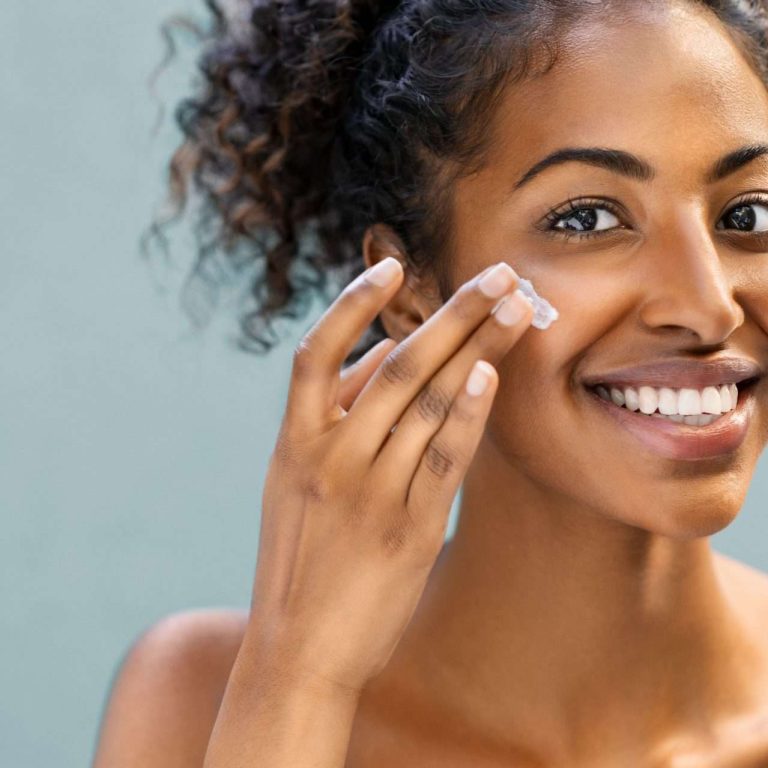 Woman applying moisturiser on face